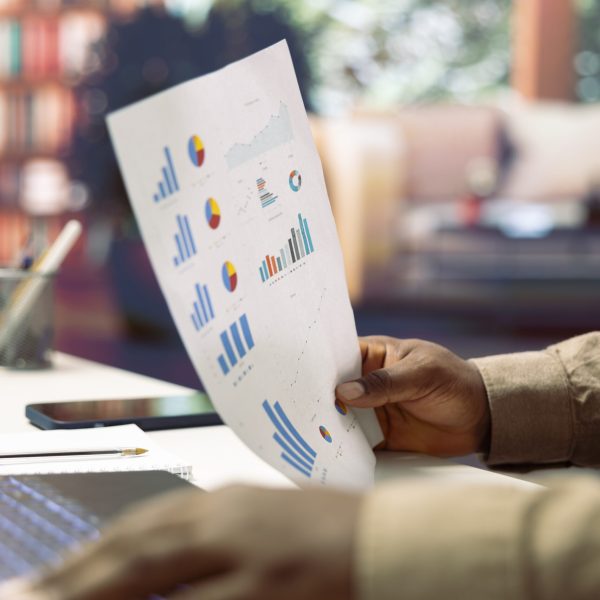 Freelancer developing a startup project and analyzing financial statistics from his home office, looking at accountancy papers. Professional analyst writing business reports, telecommuting.